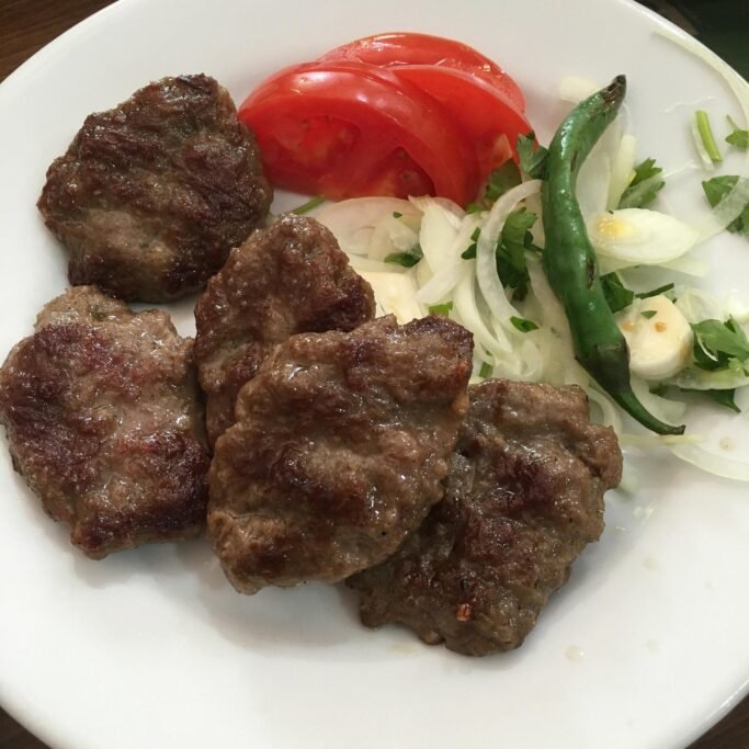 Plate of Bergama meatballs served with piyaz and grilled peppers
