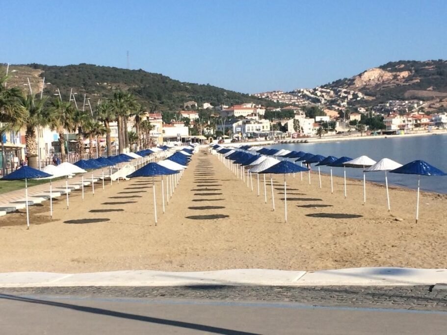 Yeni Foça Public Beach with umbrellas, clear water, and Blue Flag swimming area