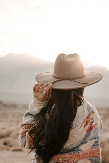 Woman wearing a wide-brimmed hat and patterned layer in a desert landscape