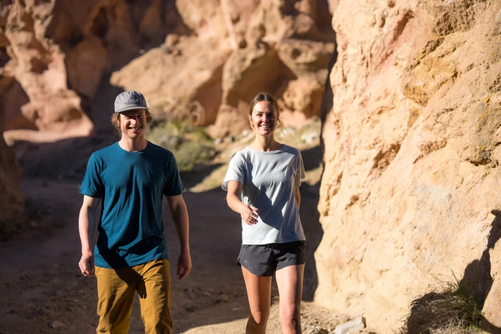Two travellers wearing lightweight T-shirts and shorts in a sunlit rocky landscape