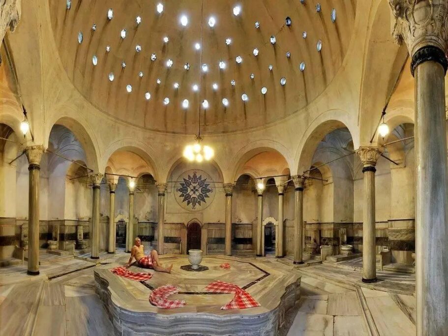 Traditional Turkish hammam interior with marble göbek taşı, arched alcoves and domed ceiling